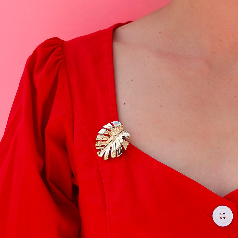 Jewel clip in the shape of a golden monstera leaf worn on a blouse