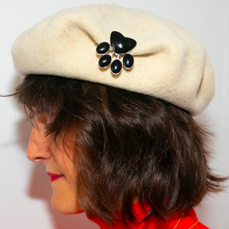 Jewel clip in the shape of a black sequined cat's paw worn on a beret