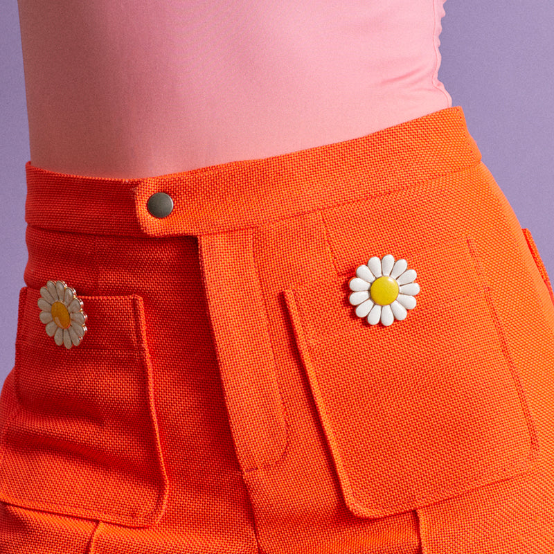 Daisy clip jewel worn on orange trouser pocket