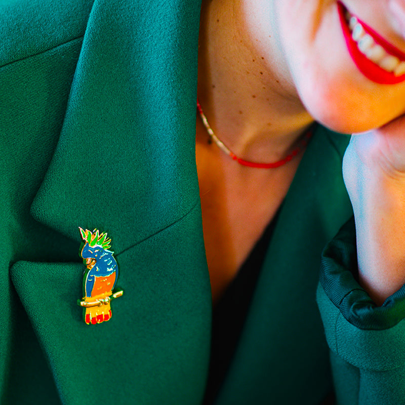 Jewel clip in the shape of a multicoloured parrot worn on a green jacket lapel