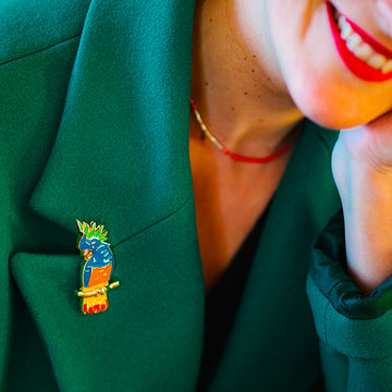 Jewel clip in the shape of a multicoloured parrot worn on a green jacket lapel