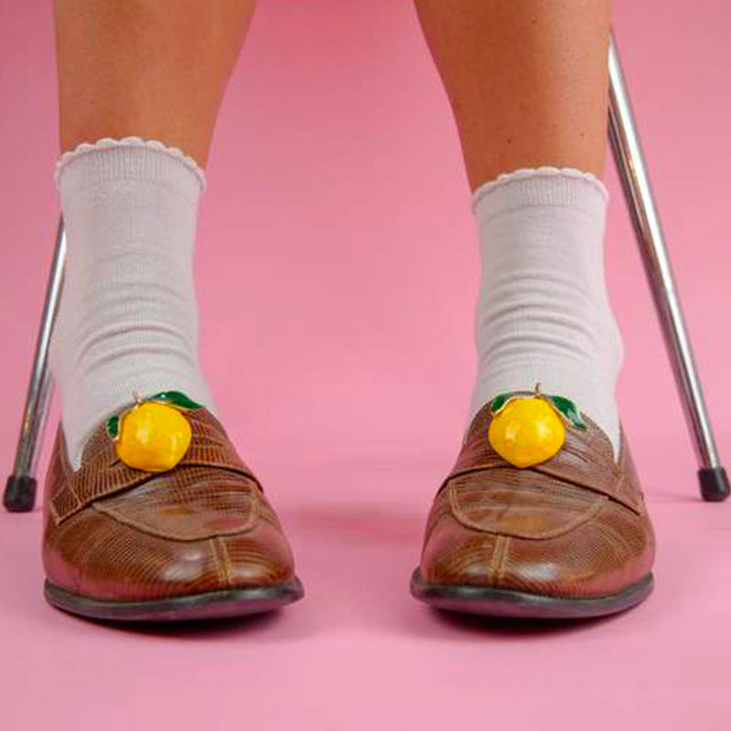 Jewel clip in the shape of a yellow lemon worn over moccasins and white socks